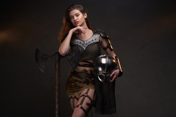 Obraz na płótnie Canvas Young woman viking posing with helmet and axe