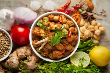 Chickpeas masala (Spicy chola or chhole curry)  garnished with fresh green coriander and ingredients. Served in a ceramic bowl. An Classic Indian typical Panjabi street food.  