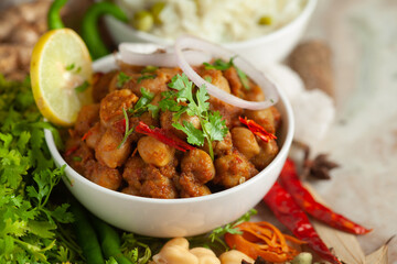 Chickpeas masala (Spicy chola or chhole curry)  garnished with fresh green coriander and ingredients. Served in a ceramic bowl. An Classic Indian typical Panjabi street food.  