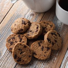 A pile of chocolate chip cookies on a wooden rustic table