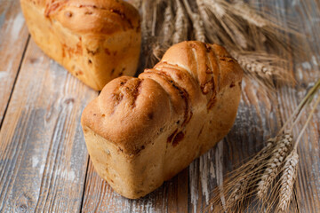 Commercial for a european bakery: golden loaf of fresh bread on vintage wooden table with spikes aside