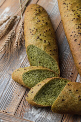 Unusual green bread with spinach, sliced and laying on a vintage wooden table, country style photo