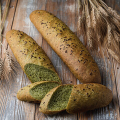 Unusual green bread with spinach, sliced and laying on a vintage wooden table, country style photo