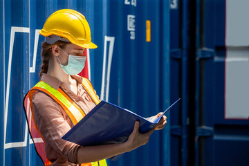 Containers woman worker wearing face mask using Folders file to inspection Containers box . female foreman Check inventory by Documents at warehouse logistic in Cargo freight ship for import export.
