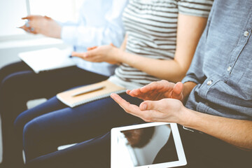 Business people clapping at meeting or conference, close-up of hands. Group of unknown businessmen and women in modern white office. Success teamwork, corporate coaching and applause concept