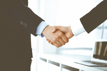 Businessman and woman shaking hands in office. Concept of handshake as success symbol in business