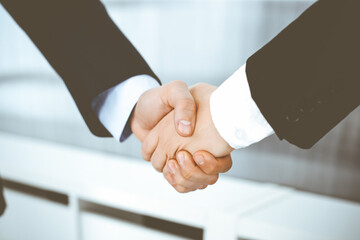 Businessman and woman shaking hands in office. Concept of handshake as success symbol in business