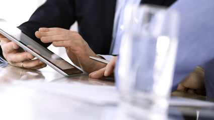 Business people using tablet computer while working together at the desk in modern office. Unknown businessman or male entrepreneur with colleague at workplace. Teamwork and partnership concept