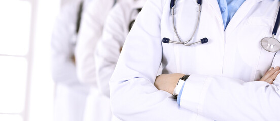 Group of modern doctors standing as a team with arms crossed in hospital office. Medical help, insurance in health care, best desease treatment and medicine concept