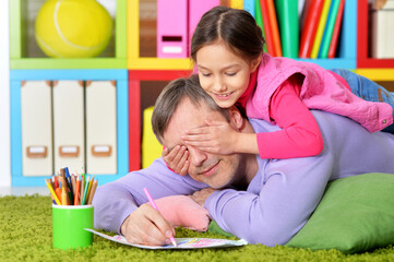 Portrait of happy father and his cute daughter drawing together