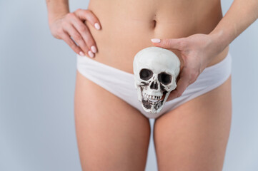 Faceless woman in underpants holding a skull on a white background.