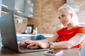 Young freelancer woman works and makes notes while working at home in quarantine lockdown. Social distancing. Self Isolation. Smiling woman working online or studying and learning while using notebook