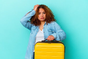 Young latin traveler curvy woman holding a suitcase isolated on blue background being shocked, she has remembered important meeting.