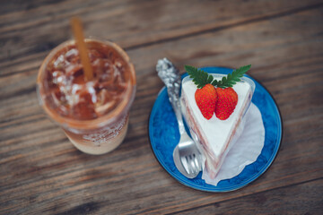 Iced coffee in plastic cups with cakes placed on the table in a cozy cafe corner.