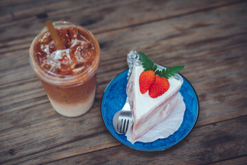 Iced coffee in plastic cups with cakes placed on the table in a cozy cafe corner.