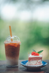 Iced coffee in plastic cups with cakes placed on the table in a cozy cafe corner.