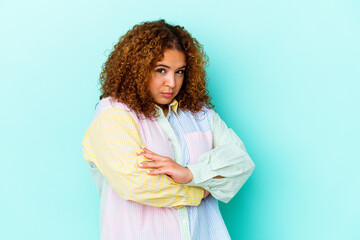 Young latin curvy woman isolated on blue background frowning face in displeasure, keeps arms folded.