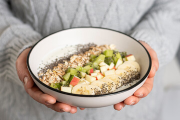 Woman holding bowl with muesli and fruits