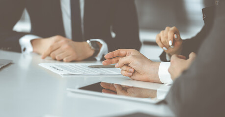 Unknown businessmen and woman sitting, working and discussing questions at meeting in modern office, close-up