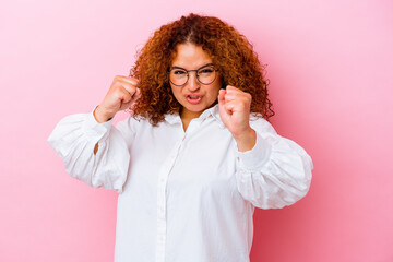 Young latin curvy woman isolated on pink background upset screaming with tense hands.
