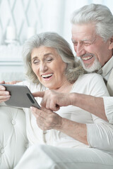 portrait of a happy senior couple using tablet at home
