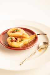 Glazed pears on a white plate with nuts and vintage spoon 