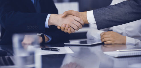 Handshake as successful negotiation ending, close-up. Unknown business people shaking hands after contract signing in modern office