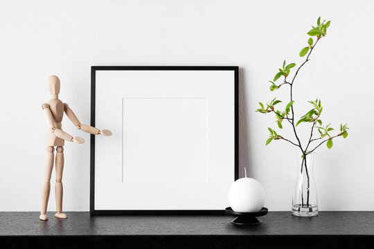 Frame mockup. Poster with plant in vase, candle and wooden human.