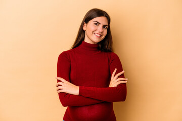 Obraz premium Young caucasian pregnant woman isolated on beige background who feels confident, crossing arms with determination.