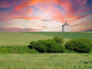 Dramatischer Himmel in Pink und Lila mit Wasserturm und Wiese