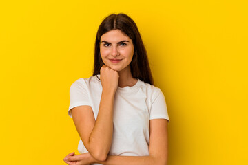 Fototapeta premium Young caucasian woman isolated on yellow background smiling happy and confident, touching chin with hand.