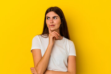 Young caucasian woman isolated on yellow background contemplating, planning a strategy, thinking about the way of a business.