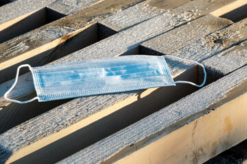 medical face mask on a bench covered with frost