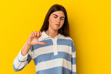 Young caucasian woman isolated on yellow background showing a dislike gesture, thumbs down....