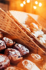 Close-up of muffins on a tray. Powdered sugar cakes. The work of the confectionery industry. Each cupcake is wrapped in paper wrapping. Vertical photo