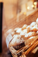 Close-up of muffins on a tray. Powdered sugar cakes. The work of the confectionery industry. Each cupcake is wrapped in paper wrapping. Vertical photo