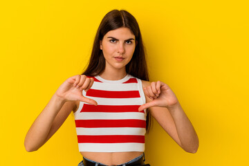 Young caucasian woman isolated on yellow background showing a dislike gesture, thumbs down....