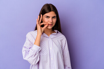 Young caucasian woman isolated on purple background with fingers on lips keeping a secret.