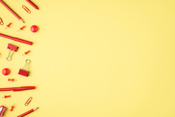 Overhead photo of red marker paperclips pen pencil and sharpener isolated on the yellow background with blank space