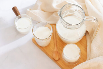 Milk drinks in clear jars and glass of milk on wooden board. Healthy drink concept.