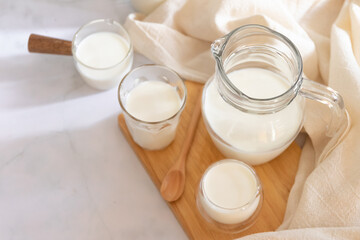 Milk drinks in clear jars and glass of milk on wooden board. Healthy drink concept.