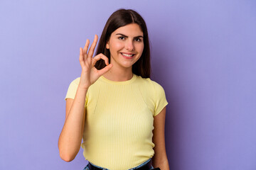 Young caucasian woman isolated on purple background cheerful and confident showing ok gesture.