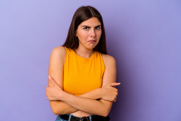 Obraz premium Young caucasian woman isolated on purple background shrugs shoulders and open eyes confused.