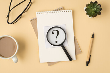 Top view photo of sticker with question mark magnifier on two organizers pen glasses plant and cup on isolated beige background