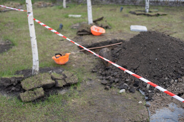 Naklejka premium wooden spade resting on the side of a hole dug into a lawn