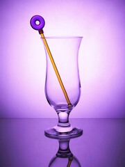 Cocktail empty glass standing on a violet background.Cocktail stick