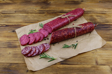 Salami sausages on craft paper on a wooden table