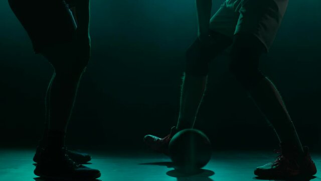 The throw-in of the ball before the start of the game in basketball competition. Two opposing players jumping for possession of the ball. Silhouette. Slow motion.