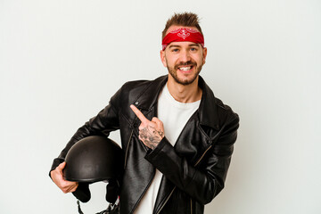 Young biker tattooed caucasian man holding a helmet isolated on white background smiling and...