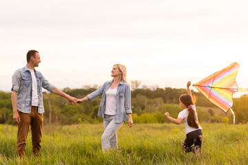 Happy family in the park evening light. The lights of a sun. Mom, dad and baby happy walk at sunset. The concept of a happy family